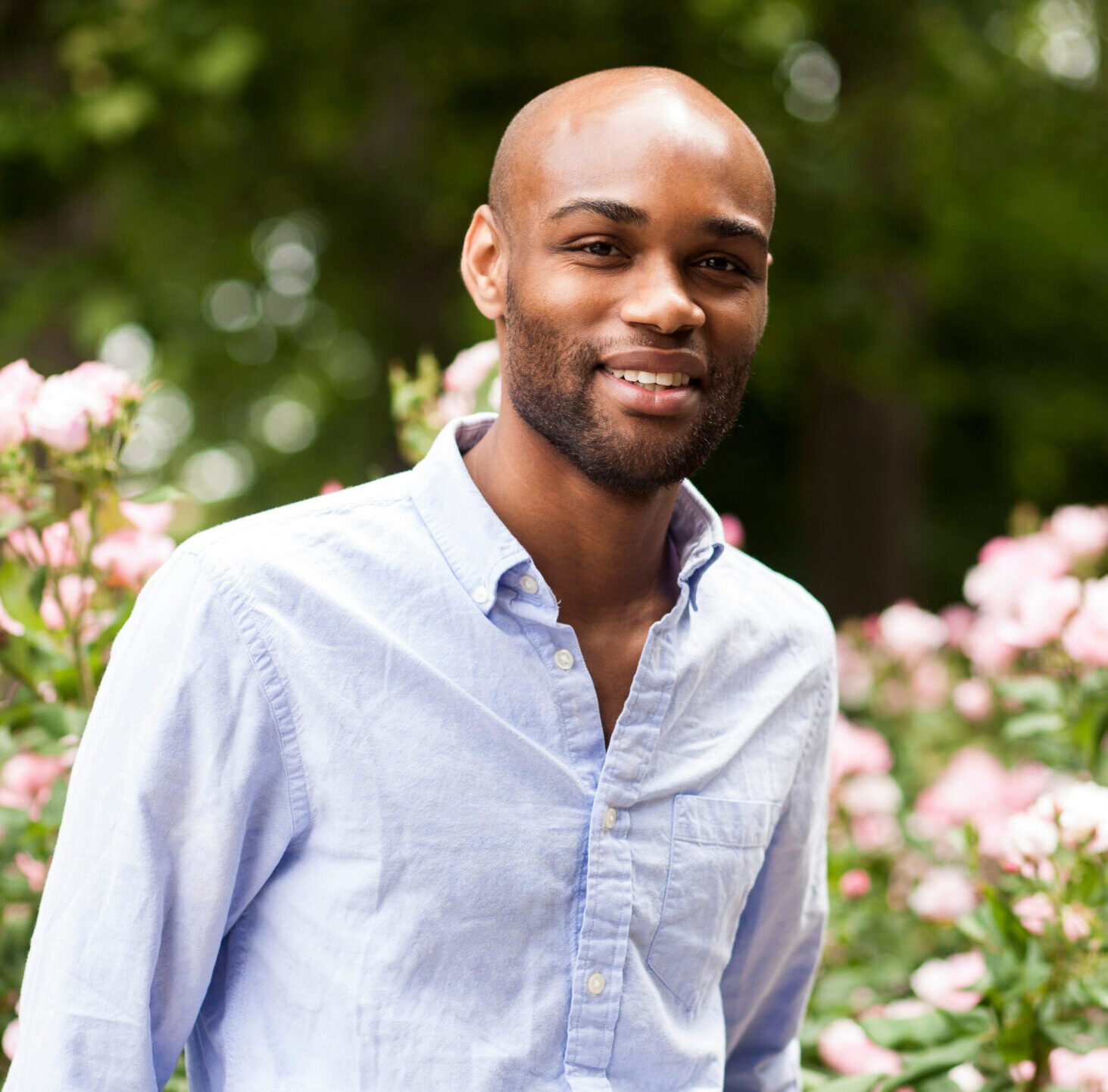 Portrait of young man leaning on railings in park